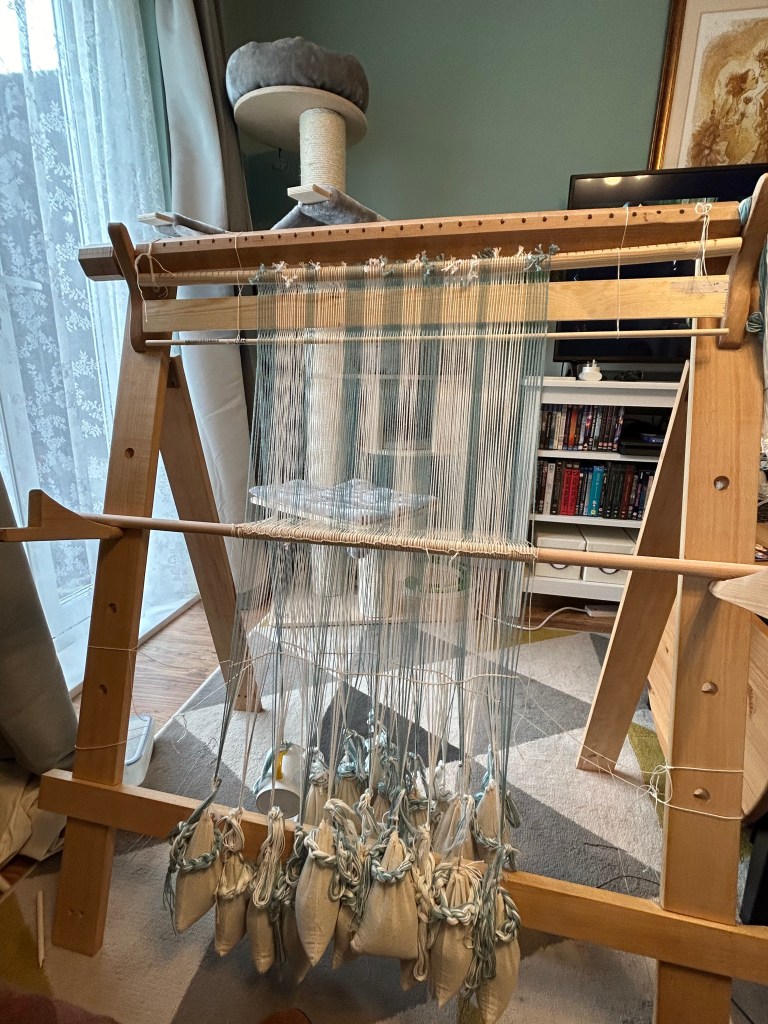 Upright warp-weighted loom set up for weaving. 