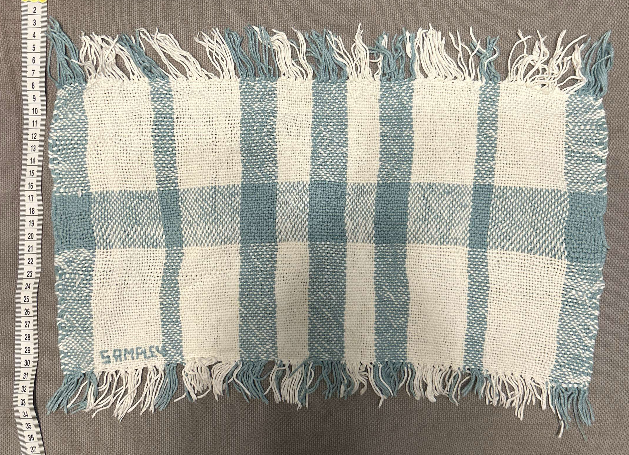 Woven fabric sample in  pale blue and white cotton yarn with uneven weave.