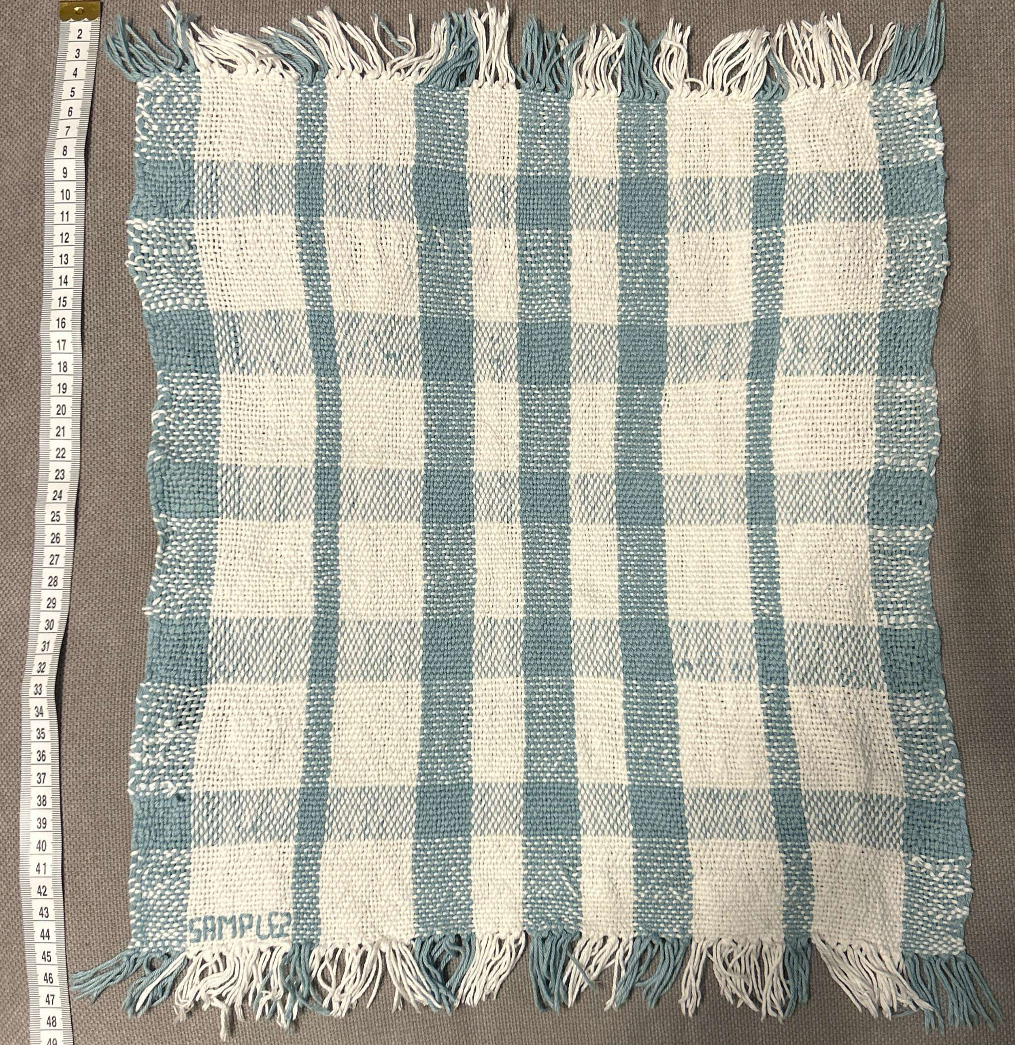 Woven fabric sample in  pale blue and white cotton yarn with uneven weave.
