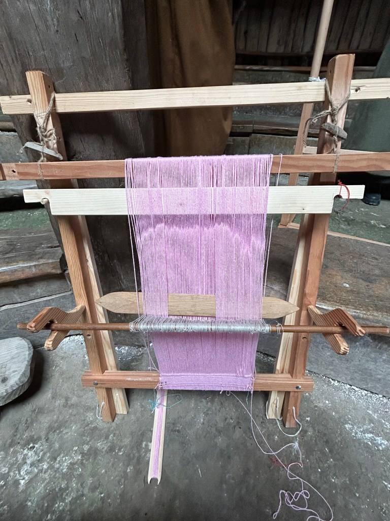 A photo of a scaled-down model two-beam vertical loom with warp. 
