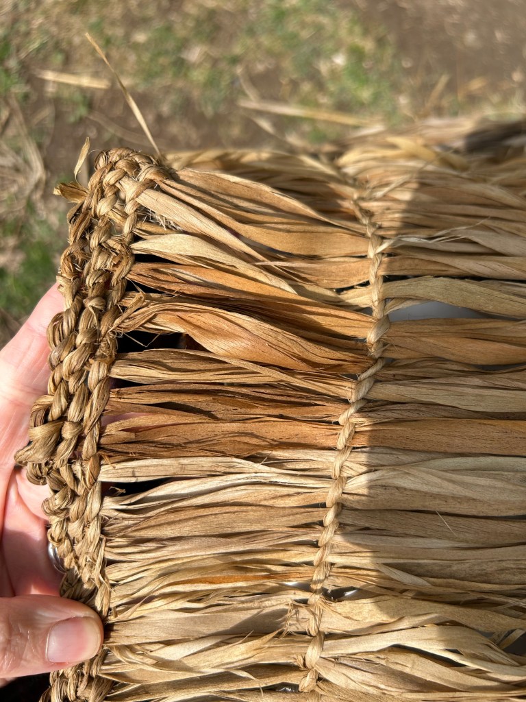 A close-up photo showing the structure of an object made from twined lime bast. In this photo, the active cordage runs from the top to the bottom of the photo and the passive fibres run left to right. There are three close-set rows of twining at the left hand side and a single row of twined fibre a few inches to the right. 