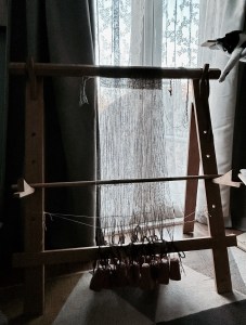 Photo showing the loom all set up and the weaving process started. Also a cat lounging in the cat tree to the right. 